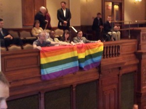 Left-wing Chicago homosexual activist Andy Thayer of Gay Liberation Network (GLN) unfurls homosexualist "rainbow flag" in the gallery of the Illinois House yesterday. Photo: Dave Smith of Illinois Family Institute -- who reports that the Illinois "gay" lobby is still a few votes shy to pass homosexuality-based "marriage" before the session ends Friday, May 31.. 